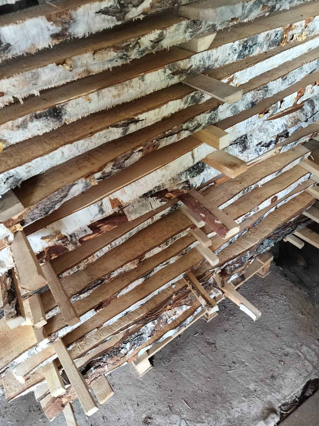 Stickered stack of bark-edge curly birch boards air-drying outdoors on a Finnish yard